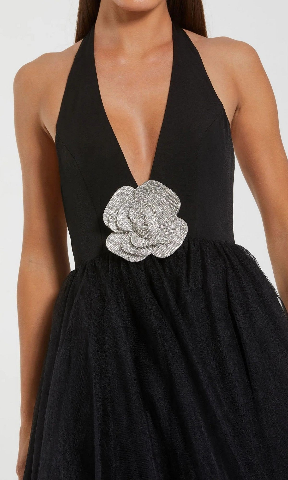 A woman wearing the Long Formal Dress: Mac Duggal 56187, a black halter ballgown featuring a deep V-neckline and a silver floral embellishment at the waist.